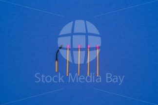 5 Matches, one burned on blue background - Stock Media Bay