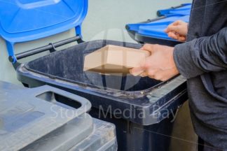 men putting cardbox in litter at home - Stock Media Bay